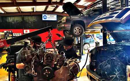 Local engine mechanics installing newly rebuilt engine on Ford truck