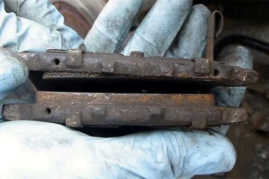 auto-service-experts-uneven-inner-outer-brake-pad-wear-san-antonio - Auto Repair San Antonio | Auto Service Experts ASE Technician holding brake pads with different levels of wear found during diagnostic at our San Antonio Brake Shop.
