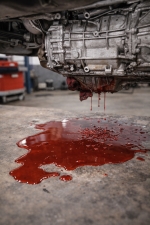 critically-low-transmission-fluid-major-leak-auto-service-experts-san-antonio – Auto Repair San Antonio | Auto Service Experts Close-up of a transmission leaking fluid onto the shop floor, showing how low fluid level prevents hydraulic pressure and causes loss of movement, diagnosed at Auto Service Experts in San Antonio