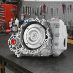 ford-escape-6f35-transmission-on-workbench – Auto Repair San Antonio | Auto Service Experts Ford Escape 6F35 transmission sitting on a clean workbench at Auto Service Experts in San Antonio, with Carlos Rodriguez, Master Technician, inspecting the bell housing and torque converter area during diagnosis